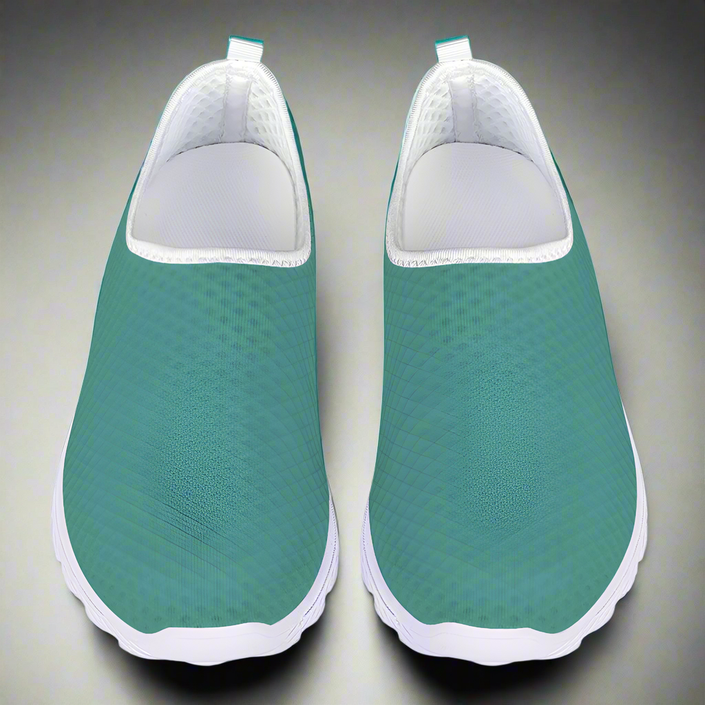 The Next Level Cushion Kicks, featuring a teal slip-on design with a textured mesh upper and white sole, are stylishly showcased against a pristine white background.
