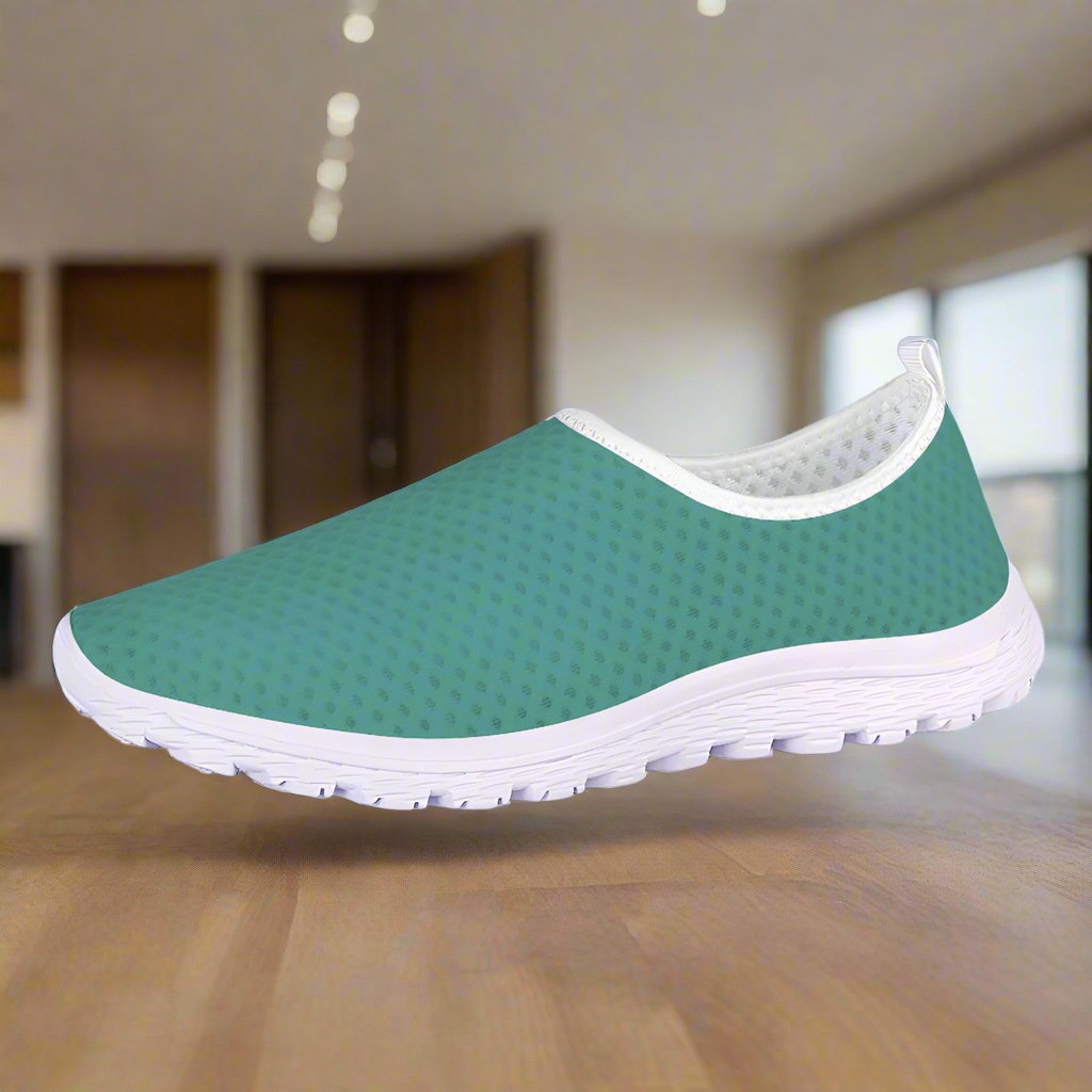 The Next Level Cushion Kicks, featuring a teal slip-on design with a textured mesh upper and white sole, are stylishly showcased against a pristine white background.