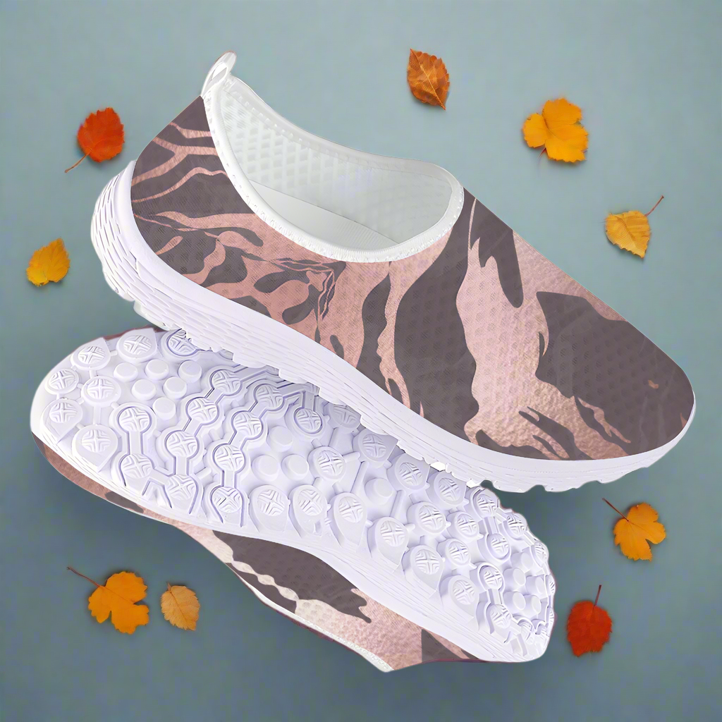 The Fall Flow Cushion Kicks are slip-on athletic shoes with a white sole and a camouflage pattern in pink, brown, and gray tones, featuring breathable mesh for maximum comfort.
