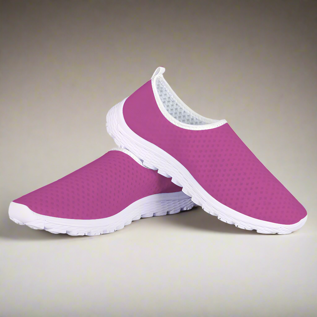 The Melanin Love Cushion Kicks are stylish slip-on sneakers in pink, featuring a slip-resistant white sole and a perforated mesh fabric design.
